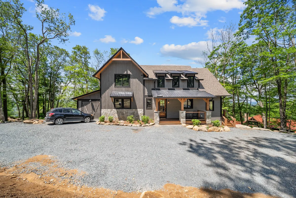 This image captures the modern architectural design of La Dolce Vita with a landscaped front yard and a large driveway. The setting evokes a welcoming and serene mountain retreat, perfectly set against nature.