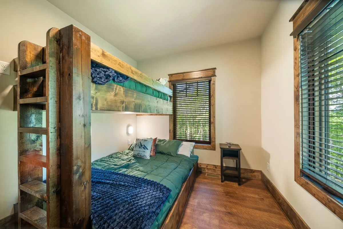 A cozy bunk bed area with a bedside table and a window with blinds. The space feels inviting and playful—ideal for sleepovers or relaxing after a day of games.