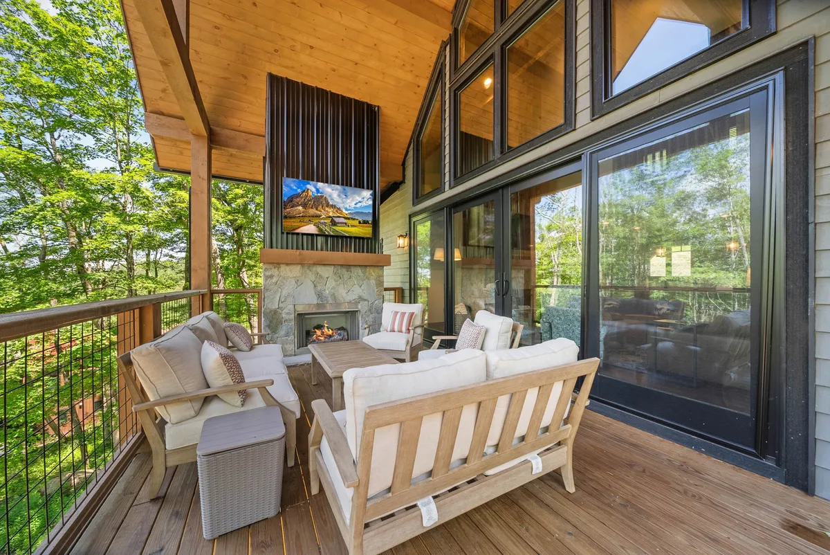 An inviting outdoor living area featuring a cozy fireplace, large windows, and comfortable seating. The setup is perfect for relaxing after a day of adventure or stargazing at night, emphasizing connection to nature and seasonal ambiance.